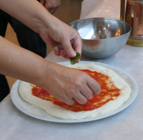 Pizza beleggen met basilicum in Napels