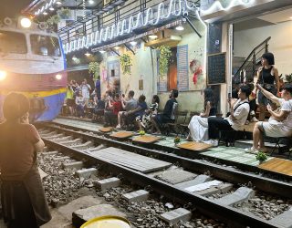 Trein raast voorbij langs terrasjes in Train Street Hanoi Vietnam