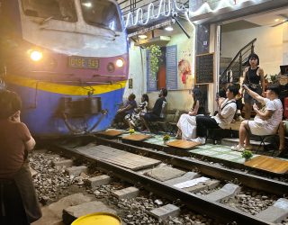 Trein raast voorbij langs terrasjes in Train Street Hanoi