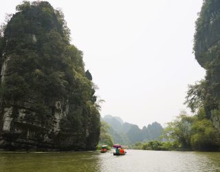 Varen op rivier tussen karstgebergte in Ninh Binh