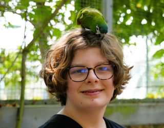 Vogel op hoofd tiener in vogelpark Hué