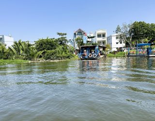 Varen langs de huizen in Mekong Delta